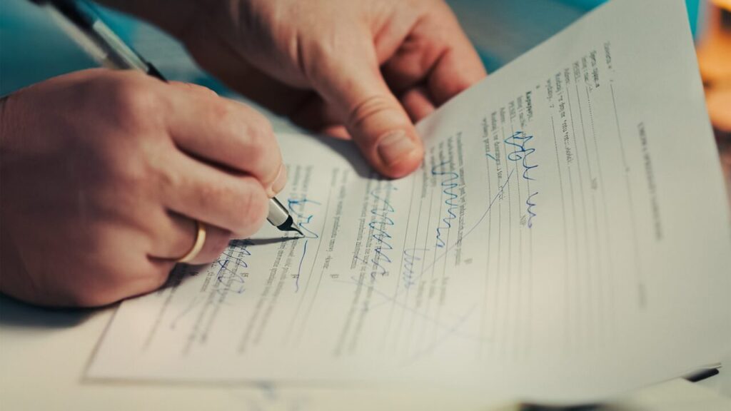 Mains signant un document avec un stylo, conditions générales de vente